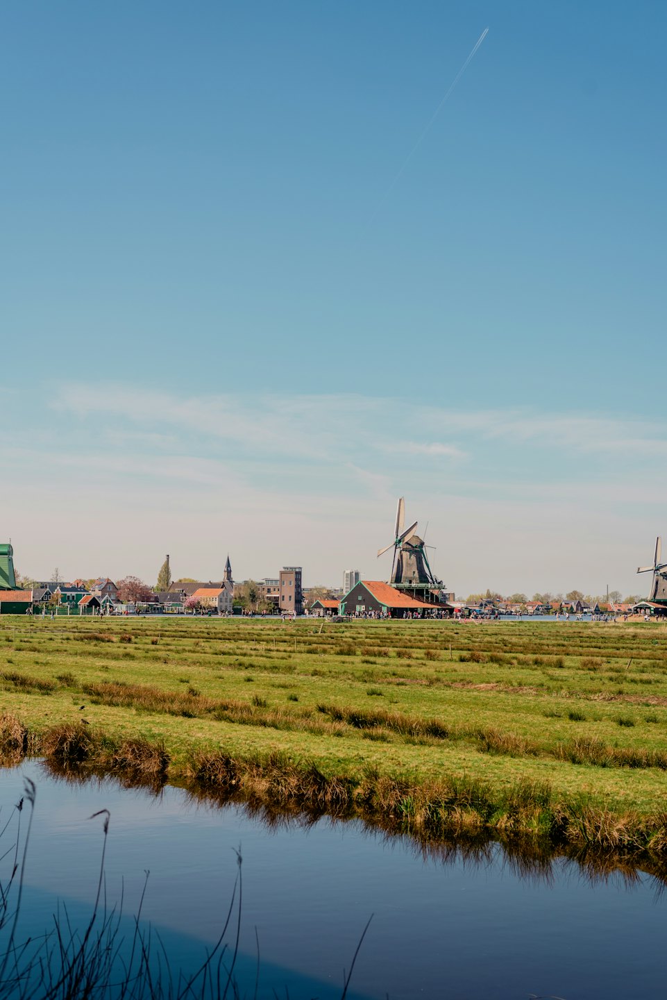 Traditionele windmolens en huizen langs een kanaal op het Nederlandse platteland.